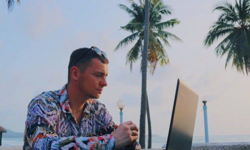 Grigori Kalinski mit Laptop unter Palmen