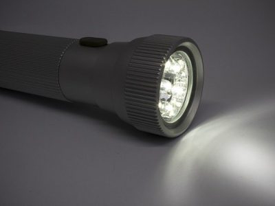Utensilien gegen Stromausfall, großes Bild mit brennender, leuchtender LED-Taschenlampe liegt auf dem Tisch